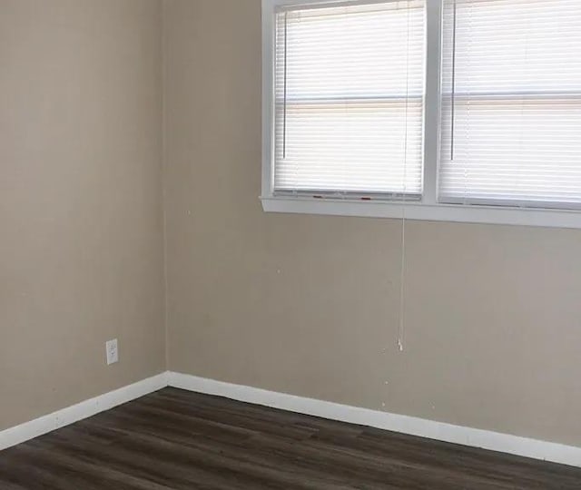 spare room with dark wood-style floors and baseboards