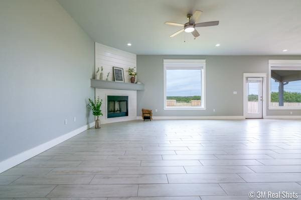 unfurnished living room with ceiling fan and a large fireplace