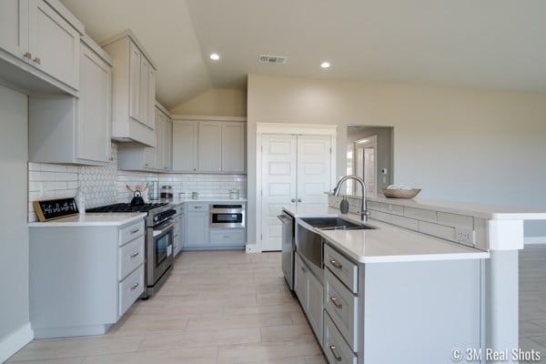 kitchen featuring stainless steel appliances, lofted ceiling, sink, and decorative backsplash