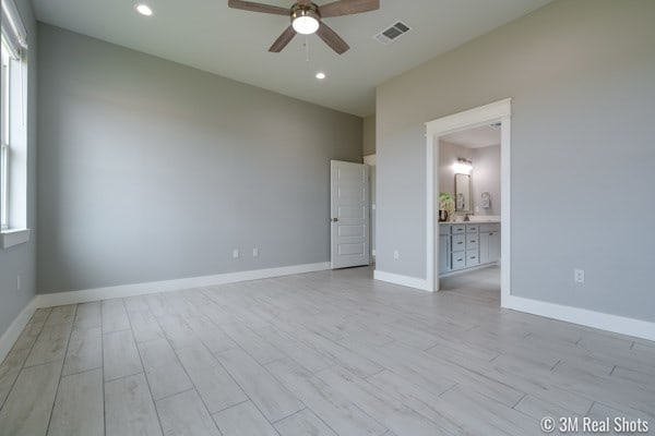 empty room with a healthy amount of sunlight, light hardwood / wood-style floors, and ceiling fan