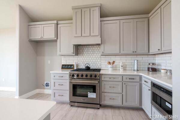 kitchen featuring stainless steel appliances, gray cabinetry, backsplash, and light hardwood / wood-style floors