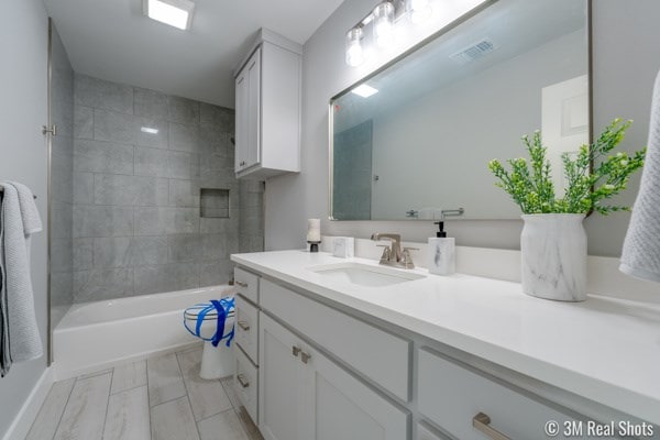 bathroom featuring tiled shower / bath combo and vanity