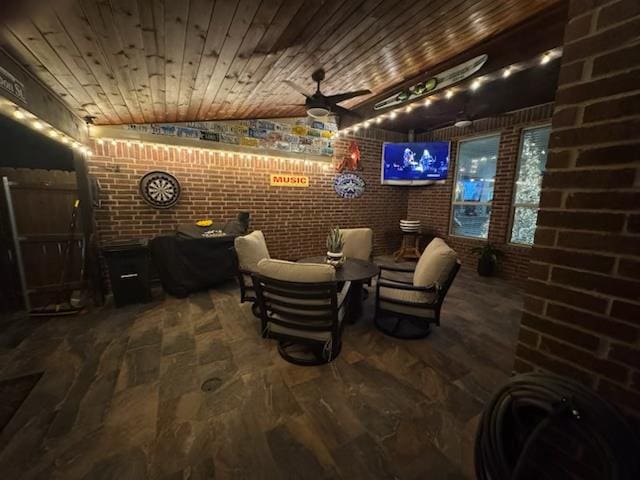 interior space with lofted ceiling, wooden ceiling, ceiling fan, and brick wall