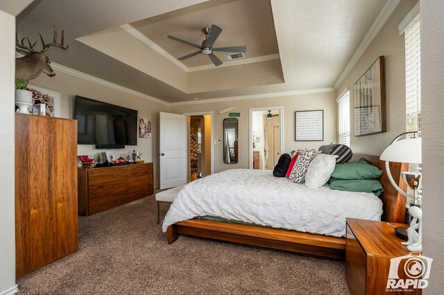 carpeted bedroom with crown molding, ceiling fan, connected bathroom, and a tray ceiling