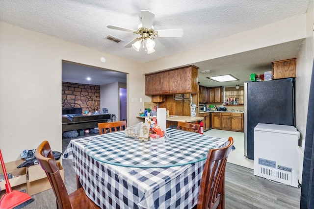 dining room with ceiling fan, wood-type flooring, and a textured ceiling