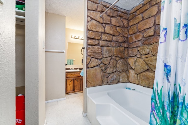 bathroom featuring vanity, a bath, and a textured ceiling