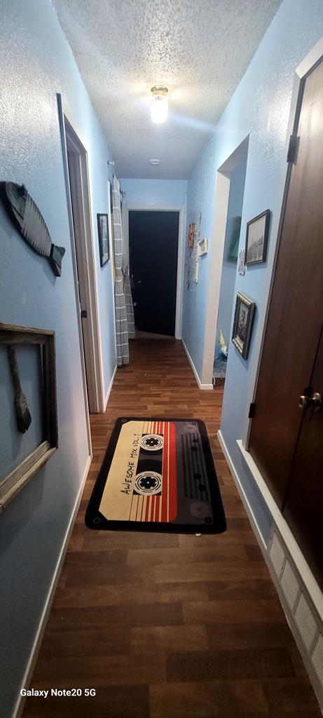 hallway featuring dark wood-type flooring and a textured ceiling