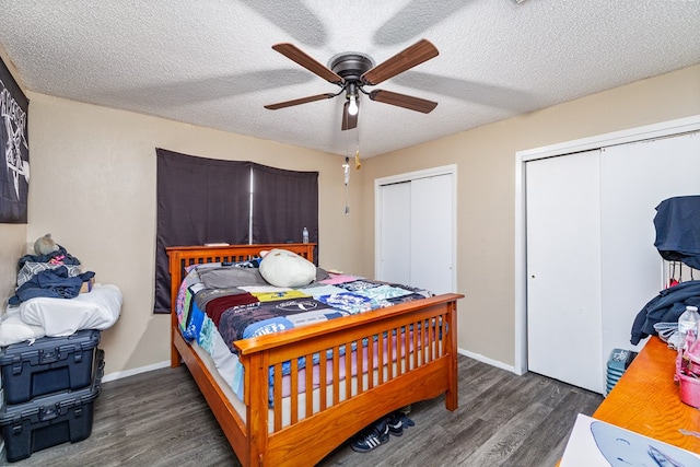 bedroom with dark hardwood / wood-style flooring, ceiling fan, a textured ceiling, and multiple closets