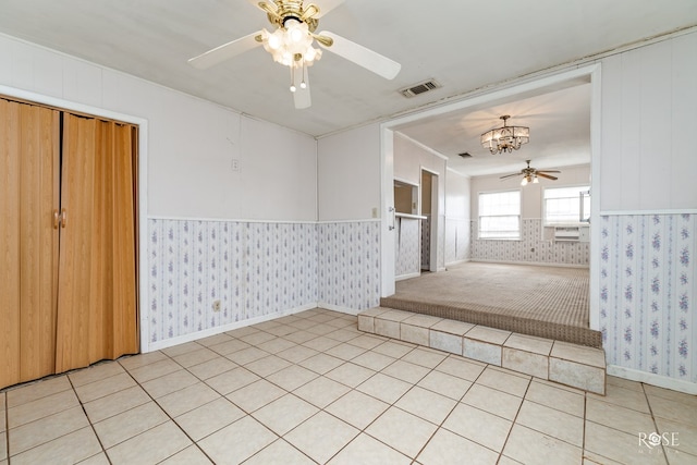 tiled spare room featuring ceiling fan with notable chandelier