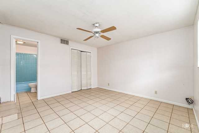 unfurnished bedroom featuring ensuite bath, ceiling fan, and a closet