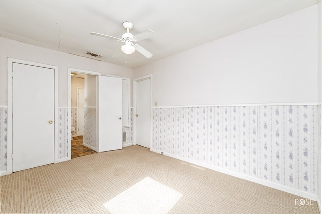 unfurnished bedroom with ceiling fan, ensuite bathroom, and carpet