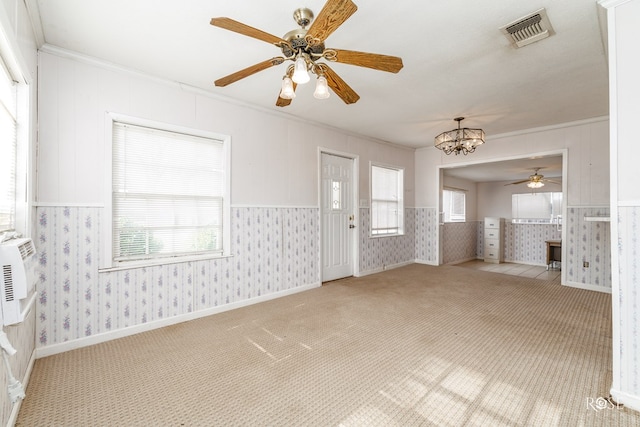 interior space featuring ornamental molding, ceiling fan with notable chandelier, a healthy amount of sunlight, and light colored carpet