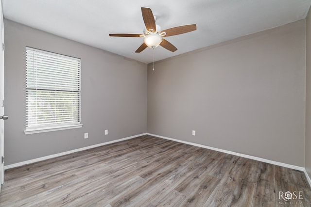 empty room featuring wood finished floors, baseboards, and ceiling fan