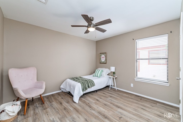 bedroom featuring a ceiling fan, baseboards, and light wood finished floors