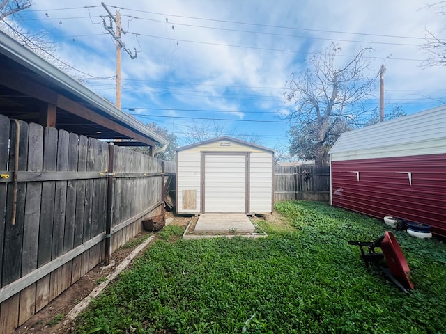 view of yard featuring a storage shed, a fenced backyard, and an outbuilding