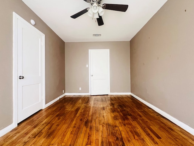 unfurnished room featuring ceiling fan, wood finished floors, visible vents, and baseboards