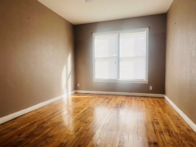 empty room with wood-type flooring and baseboards