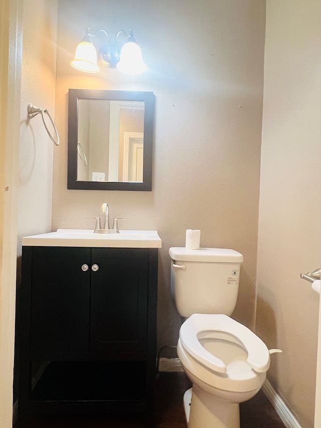 bathroom featuring toilet, baseboards, and vanity