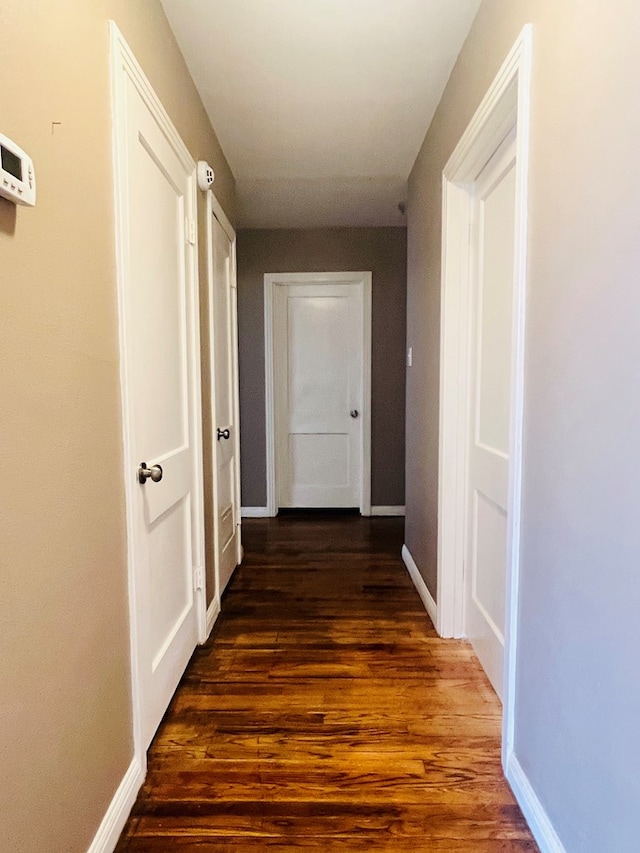 hall featuring dark wood-style flooring and baseboards