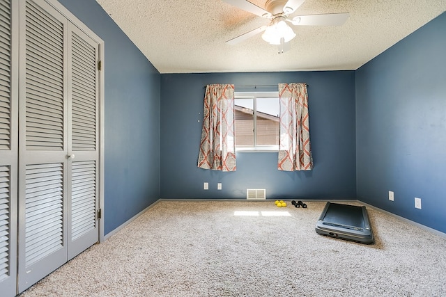 unfurnished bedroom with ceiling fan, carpet, a textured ceiling, and a closet