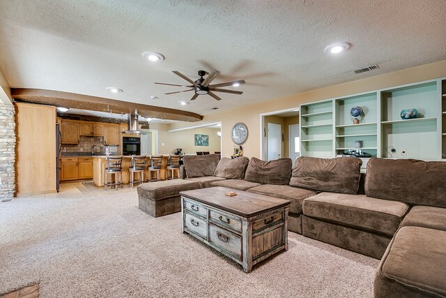 carpeted living room featuring ceiling fan and a textured ceiling