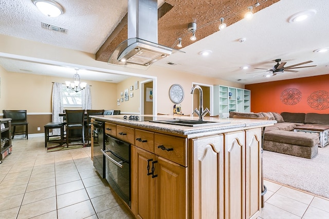 kitchen featuring island range hood, sink, a kitchen island with sink, light tile patterned floors, and a textured ceiling