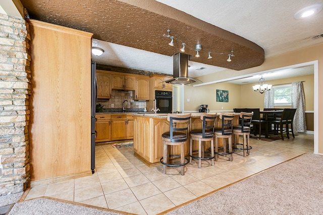 kitchen featuring a kitchen bar, a center island, a textured ceiling, light tile patterned floors, and black oven