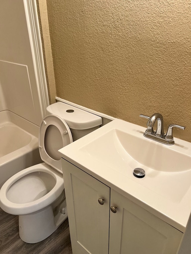 full bathroom featuring wood-type flooring, toilet, bathing tub / shower combination, and vanity