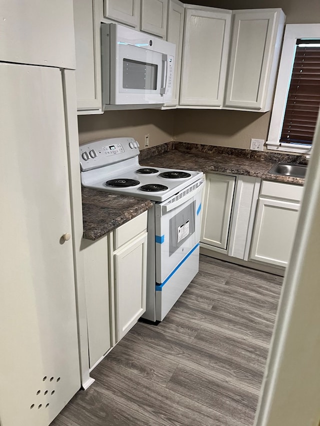 kitchen featuring dark hardwood / wood-style flooring, white appliances, and white cabinets