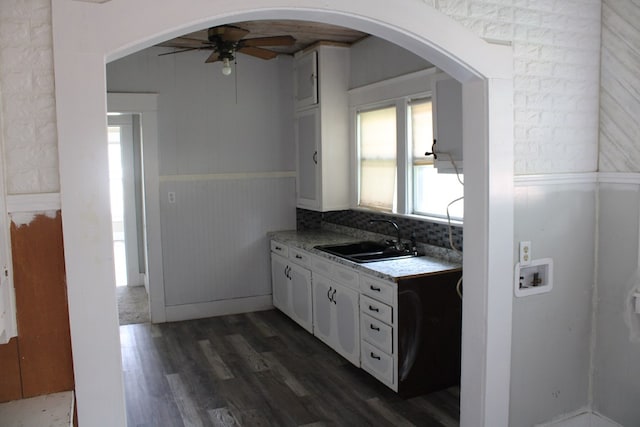 1002 Broadway St, Ballinger, TX 76821 - kitchen featuring ceiling fan, dark wood-style flooring, white cabinetry, light countertops, and a wainscoted wall