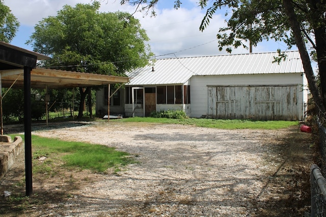 1002 Broadway St, Ballinger, TX 76821 - view of front of property featuring driveway, a metal roof, and a sunroom