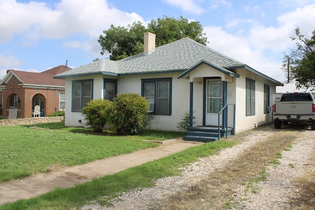 1002 Broadway St, Ballinger, TX 76821 - view of front of house with a chimney, a shingled roof, stucco siding, and a front yard