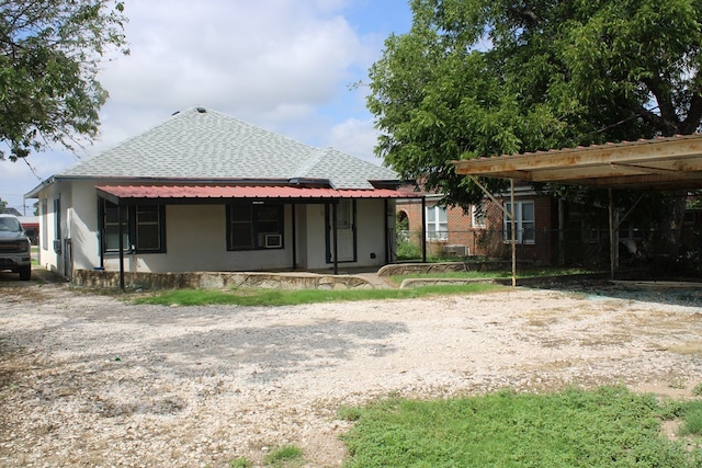 1002 Broadway St, Ballinger, TX 76821 - rear view of house with stucco siding, a shingled roof, and gravel driveway