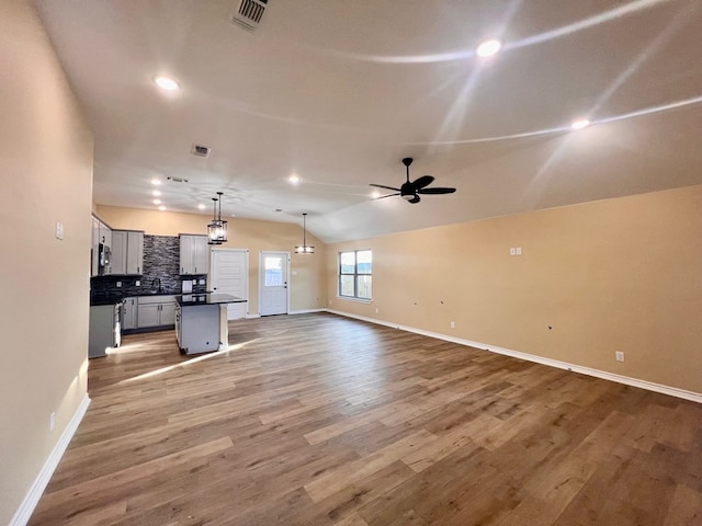 unfurnished living room featuring lofted ceiling, sink, wood-type flooring, and ceiling fan