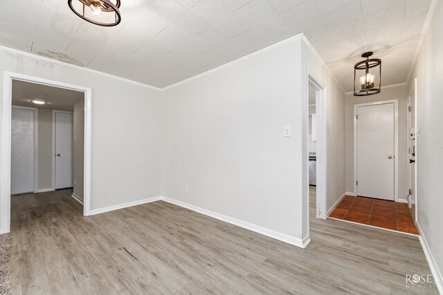 spare room with ornamental molding, a chandelier, and light hardwood / wood-style flooring