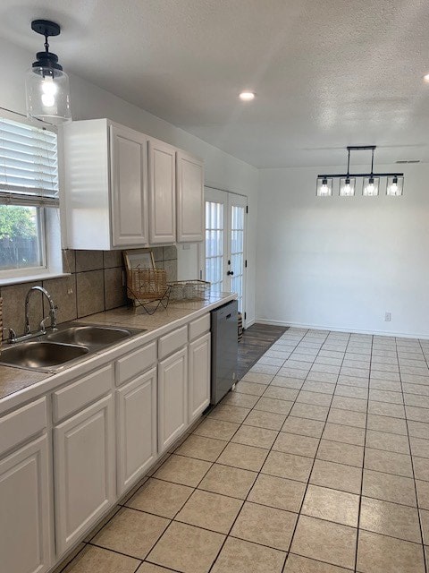 kitchen with white cabinetry, dishwasher, sink, backsplash, and hanging light fixtures