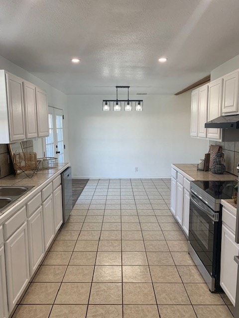 kitchen with stainless steel appliances, white cabinetry, pendant lighting, and light tile patterned floors