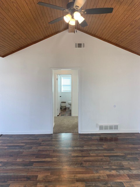 empty room with ceiling fan, lofted ceiling, dark wood-type flooring, and wood ceiling