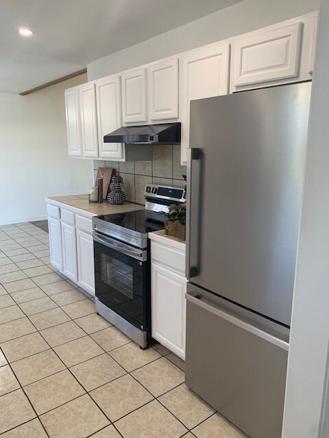 kitchen featuring white cabinetry, tasteful backsplash, stainless steel appliances, and light tile patterned flooring