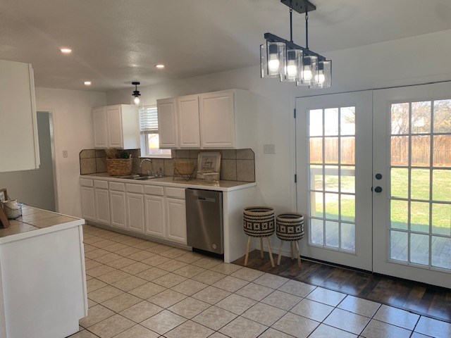 kitchen with french doors, decorative light fixtures, stainless steel dishwasher, decorative backsplash, and white cabinets