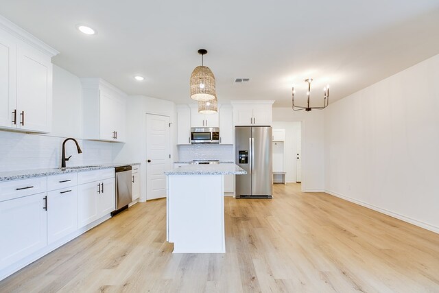 kitchen with stainless steel appliances, tasteful backsplash, light stone countertops, and white cabinets