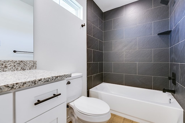 full bathroom with vanity, tiled shower / bath, hardwood / wood-style floors, and toilet