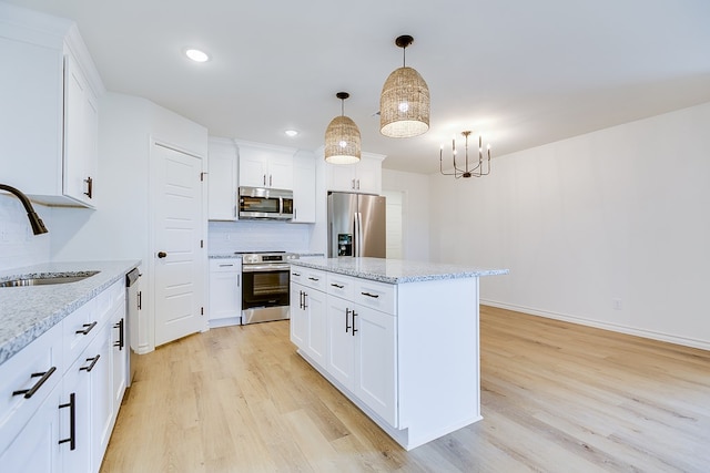 kitchen featuring sink, white cabinetry, decorative light fixtures, a center island, and stainless steel appliances