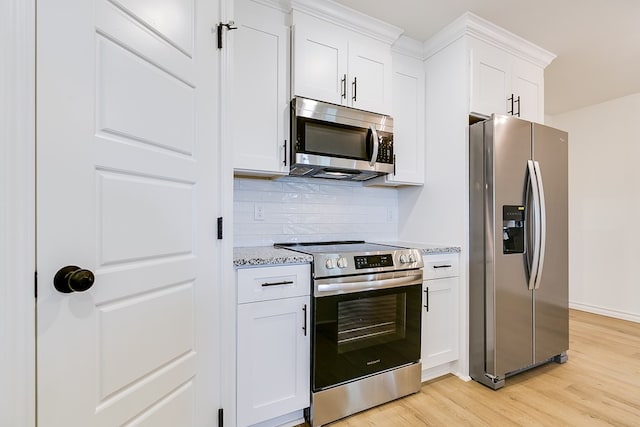 kitchen with white cabinetry, stainless steel appliances, light stone countertops, and light wood-type flooring