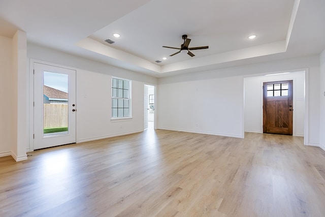 foyer entrance featuring light hardwood / wood-style flooring, a wealth of natural light, and a raised ceiling