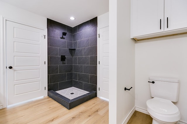 bathroom with hardwood / wood-style floors, toilet, and tiled shower