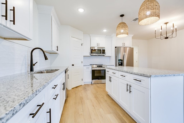 kitchen featuring stainless steel appliances, hanging light fixtures, sink, and white cabinets