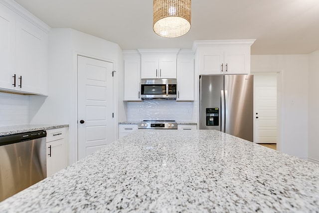 kitchen with light stone countertops, decorative backsplash, stainless steel appliances, and white cabinets