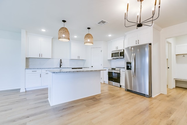 kitchen featuring light hardwood / wood-style flooring, appliances with stainless steel finishes, white cabinetry, hanging light fixtures, and a center island