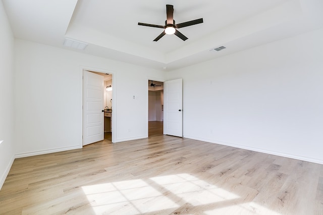 unfurnished bedroom featuring a raised ceiling, ceiling fan, and light wood-type flooring